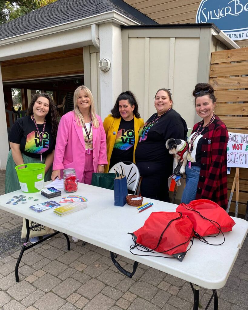 A group of staff stands smiling at a KSAC booth