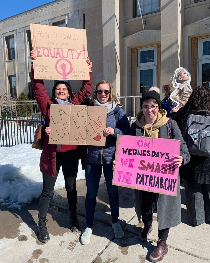 Young people hold up cardboard signs with messages supporting women's equality